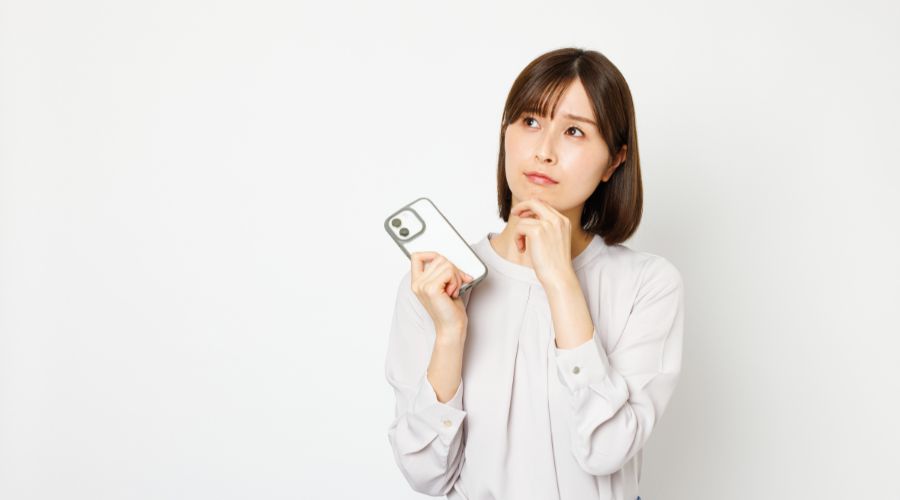 スマートホンを片手に悩んでいる女性